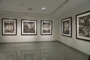 Installation view of five black and white photographs with figures.