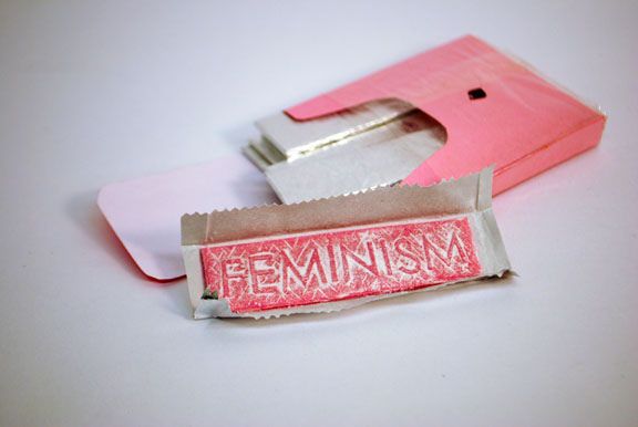 Mint chewing gum with the word Feminism embedded, paper, plastic sleeve and Wrigley's foil chewing gum wrappers