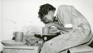 Woman working at clay wheel.