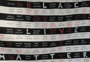 Black Lives Matter banner with black and white stripes and names.