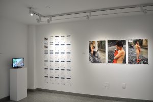 Installation view of three photographs, small tv and twenty-four sheets of letter sized paper with text. .