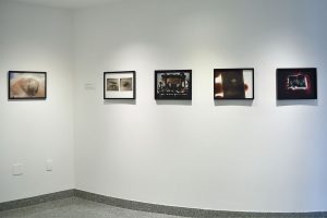 Installation view of five photographs with images of people.