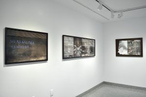Installation view of three photographs with black frames, figures and seismic register lines.