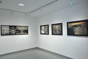 Installation view of four photographs with black frames, figures and seismic register lines.
